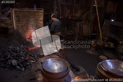 Image of young traditional Blacksmith working with open fire