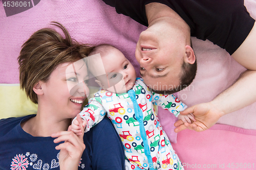 Image of Top view of smiling young couple lying with their baby