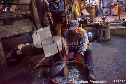 Image of blacksmith workers using mechanical hammer at workshop