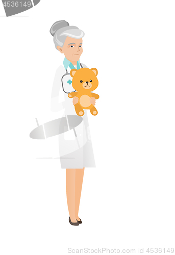 Image of Senior caucasian pediatrician holding teddy bear.