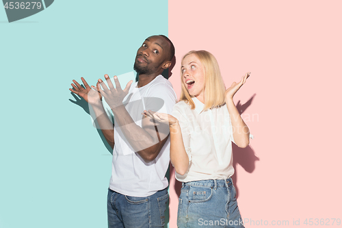 Image of Beautiful female and male portrait on pink and blue studio backgroud. The young emotional couple