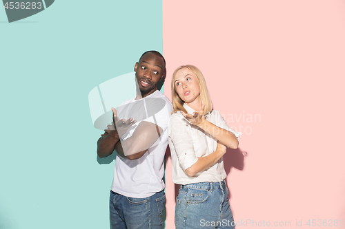 Image of Beautiful female and male portrait on pink and blue studio backgroud. The young emotional couple