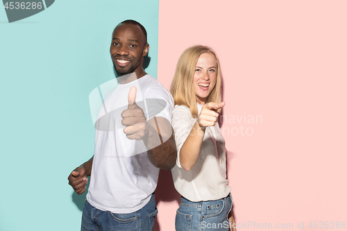 Image of The happy couple point you and want you, half length closeup portrait on studio background.