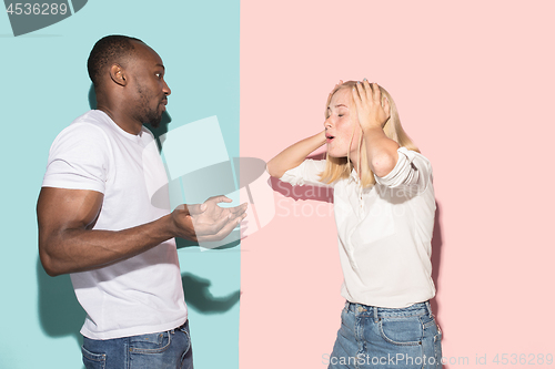 Image of Beautiful female and male portrait on pink and blue studio backgroud. The young emotional couple