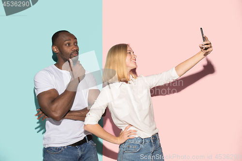 Image of Mixed raced couple of students taking common selfie with phone. Caucasian girl and her African boyfriend posing at studio .