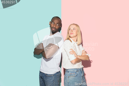 Image of Beautiful female and male portrait on pink and blue studio backgroud. The young emotional couple