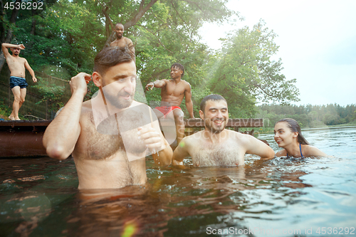 Image of Enjoying river party with friends. Group of beautiful happy young people at the river together