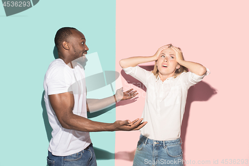 Image of Beautiful female and male portrait on pink and blue studio backgroud. The young emotional couple