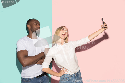 Image of Mixed raced couple of students taking common selfie with phone. Caucasian girl and her African boyfriend posing at studio .