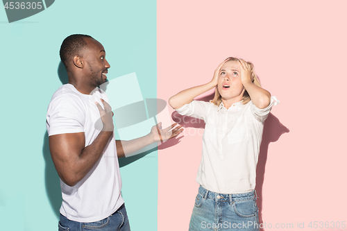 Image of Beautiful female and male portrait on pink and blue studio backgroud. The young emotional couple