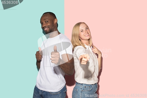 Image of The happy couple point you and want you, half length closeup portrait on studio background.