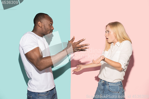 Image of Beautiful female and male portrait on pink and blue studio backgroud. The young emotional couple