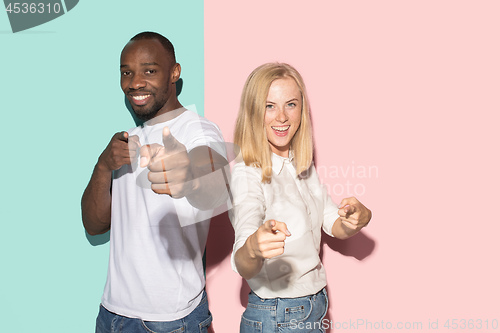 Image of The happy couple point you and want you, half length closeup portrait on studio background.