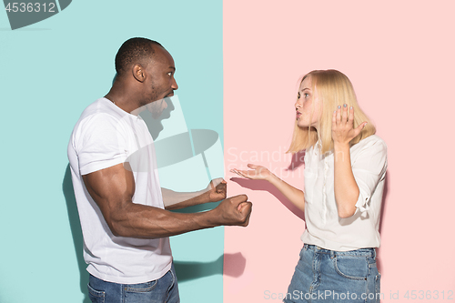 Image of Beautiful female and male portrait on pink and blue studio backgroud. The young emotional couple