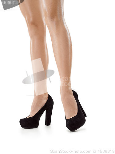 Image of Tanned female legs in high heels isolated on white background.