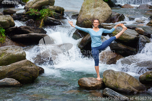 Image of Woman doing Ashtanga Vinyasa Yoga asana outdoors at waterfall