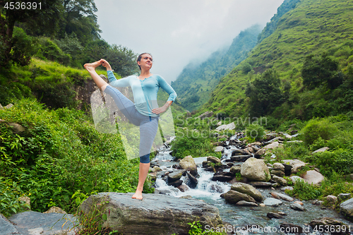 Image of Woman doing Ashtanga Vinyasa Yoga asana outdoors at waterfall