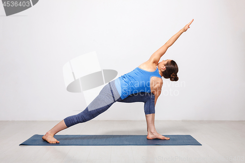 Image of Woman doing Ashtanga Vinyasa yoga asana Parivrtta parsvakonasana