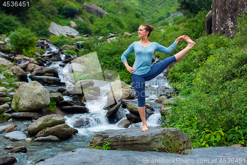 Image of Woman doing Ashtanga Vinyasa Yoga asana outdoors at waterfall