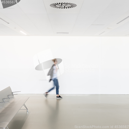 Image of Motion blur of woman walking at contemporary white empty hallway