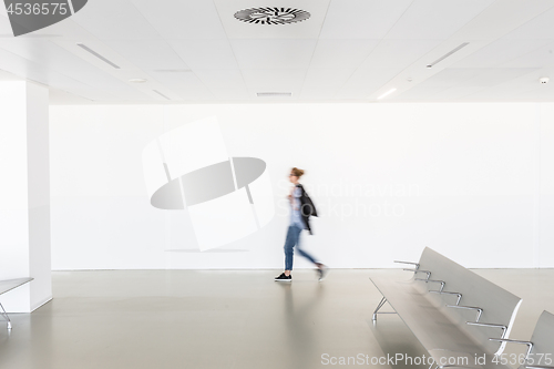 Image of Motion blur of woman walking at contemporary white empty hallway