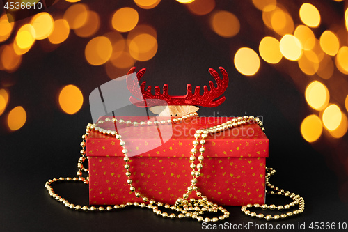 Image of Christmas decoration gift box with hidden reindeer figure on bla