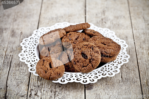 Image of Fresh baked chocolate chip cookies heap on white plateon rustic 