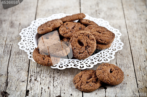 Image of Fresh baked chocolate chip cookies heap on white plateon rustic 