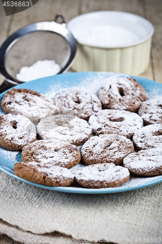 Image of Fresh baked chocolate chip cookies with sugar powder on blue pla