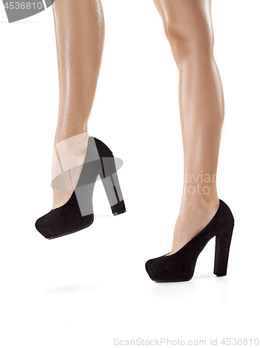 Image of Tanned female legs in high heels isolated on white background.