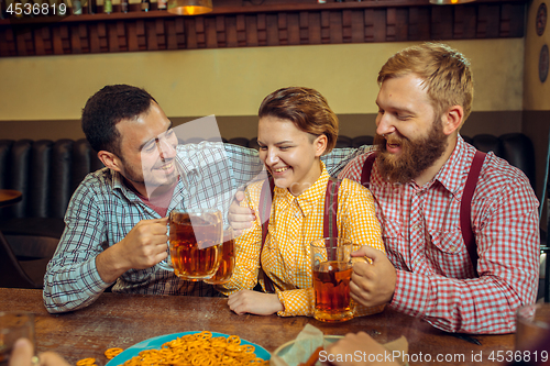 Image of people, leisure, friendship and communication concept - happy friends drinking beer, talking and clinking glasses at bar or pub