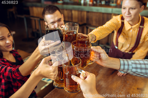 Image of people, leisure, friendship and communication concept - happy friends drinking beer, talking and clinking glasses at bar or pub
