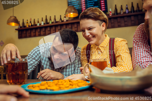 Image of people, leisure, friendship and communication concept - happy friends drinking beer, talking and clinking glasses at bar or pub
