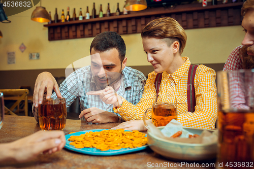 Image of people, leisure, friendship and communication concept - happy friends drinking beer, talking and clinking glasses at bar or pub