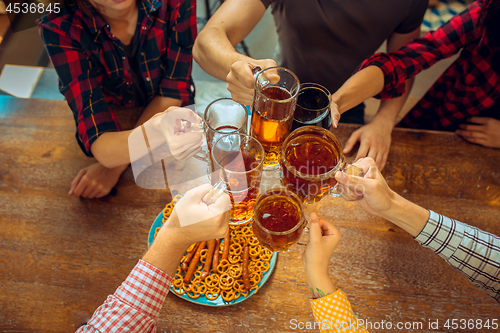 Image of people, leisure, friendship and communication concept - happy friends drinking beer, talking and clinking glasses at bar or pub