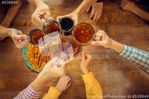 Image of people, leisure, friendship and communication concept - happy friends drinking beer, talking and clinking glasses at bar or pub