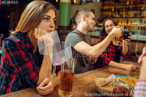 Image of people, leisure, friendship and communication concept - happy friends drinking beer, talking and clinking glasses at bar or pub