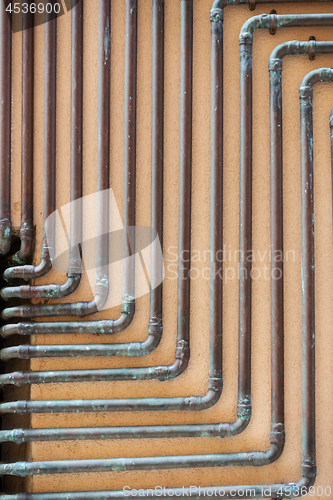 Image of some copper tubes outside on a wall