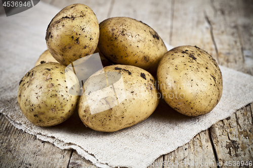 Image of Fresh organic dirty potatoes heap closeup on linen tablecloth on