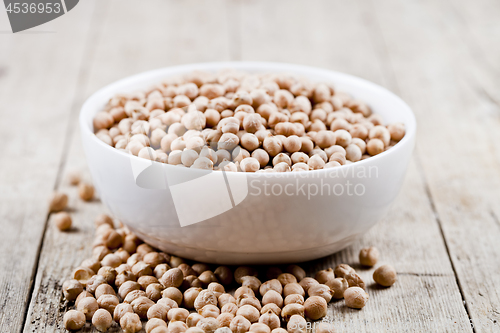Image of Fresh raw organic chickpeas in white ceramic bowl on rustic wood