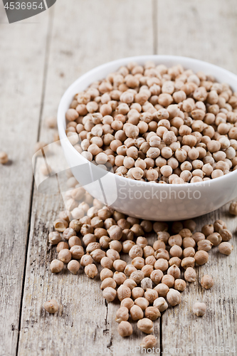 Image of Fresh raw organic chickpeas in white ceramic bowl on rustic wood