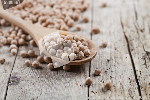 Image of Fresh raw organic chickpeas in wooden spoon on rustic wooden tab