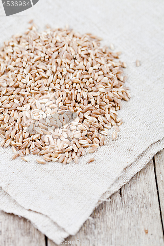 Image of Dry raw organic wheat grain heap on linen tablecloth on rustic w