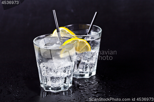 Image of Two glasses of fresh cold carbonated water with ice cubes and le