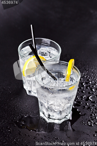 Image of Two glasses of fresh cold carbonated water with ice cubes and le