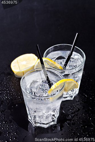 Image of Two glasses of fresh cold carbonated water with ice cubes and le