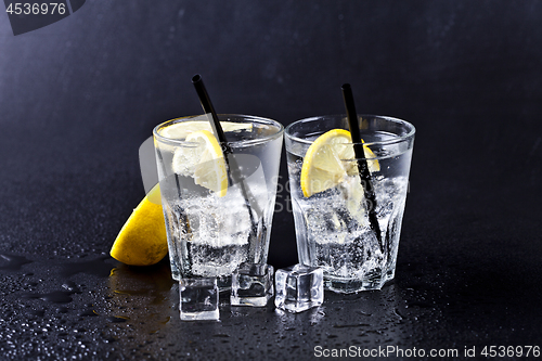 Image of Glass of fresh cold carbonated water with ice cubes and lemon sl