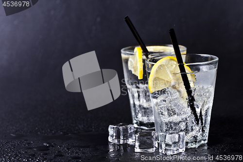 Image of Glass of fresh cold carbonated water with ice cubes and lemon sl