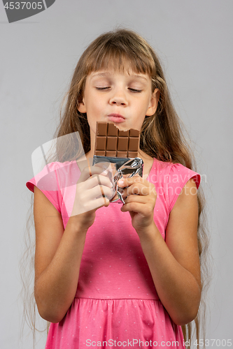 Image of Eight-year-old girl with pleasure eats chocolate bar