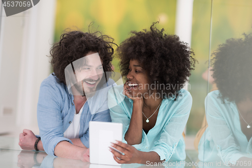 Image of Couple relaxing together at home with tablet computer